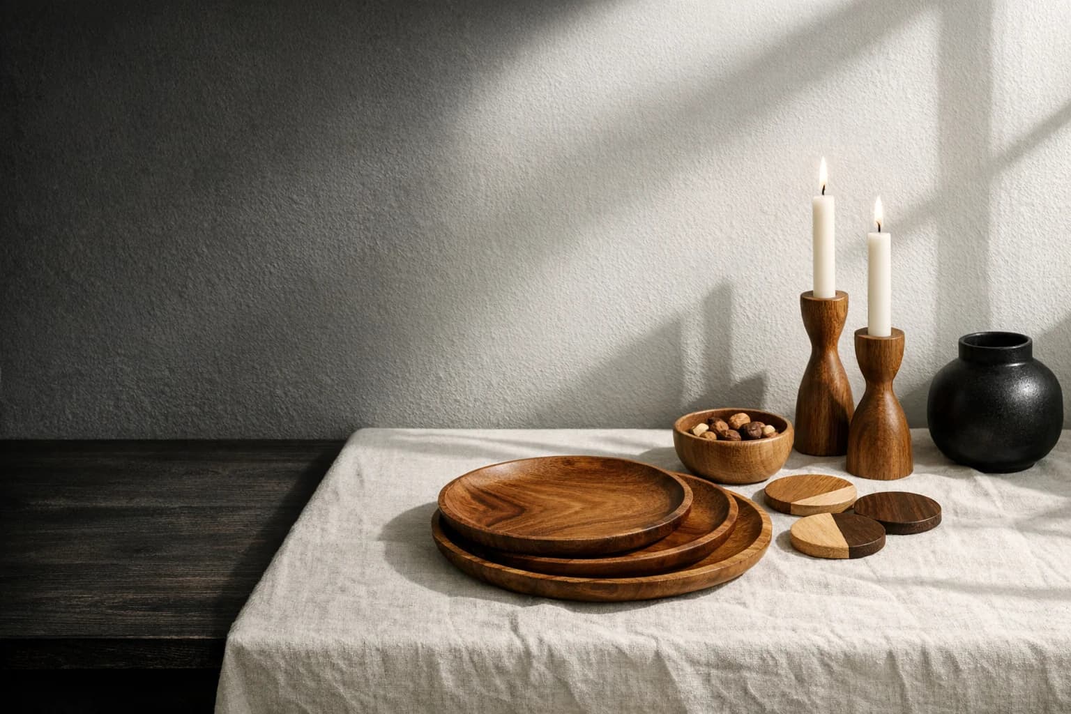 Platos de madera, portavasos y candelabros sobre una mesa de lino